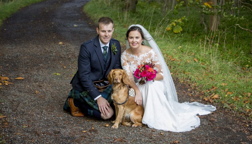 bride groom and dog sitting together at their wedding